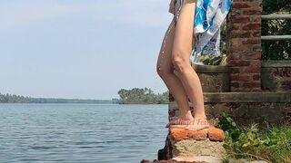 Shameless tourist girl pissing on the public waterfront taking off her swimsuit.