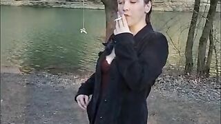 Opening a new pack and smoking by the water in a dress and jean jacket