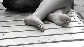 Women's feet on a park bench.