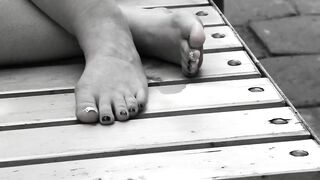 Women's feet on a park bench.