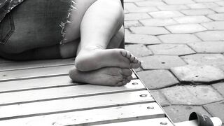 Women's feet on a park bench.