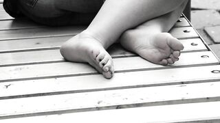 Women's feet on a park bench.