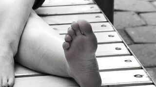 Women's feet on a park bench.